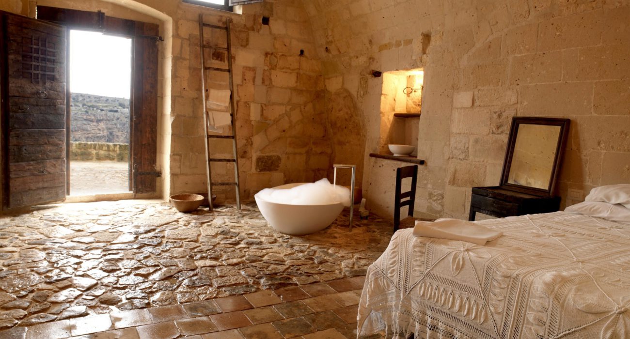 Sextantio Le Grotte della Civita cave number 15 features an original stone sink, while the lavatories are housed in a cosy and detached environment you access through a wooden door.